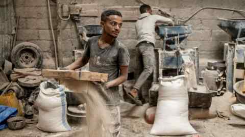 A worker sifts grain at a market where several flours, including teff, are sold in Addis Ababa, Ethiopia