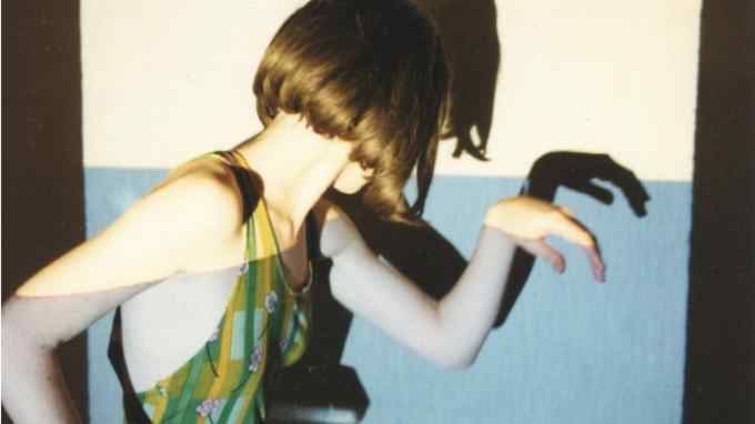 ‘Love Diamond’, 1998, by Miranda July: a still of the artist Miranda July standing in profile with her head turned away against a white and blue backddrop