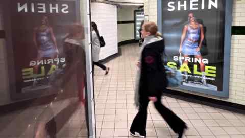 A person walks past an advertisement for Shein in London