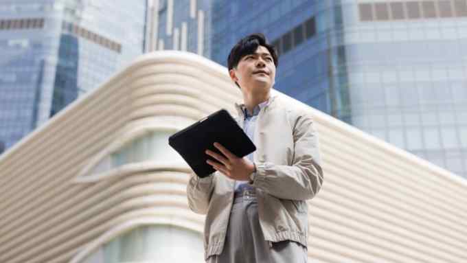 An young Asian man wearing casual clothes holding a digital tablet