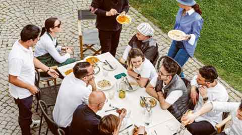 Massimo Bottura stands at the head of the table during a family meal alfresco