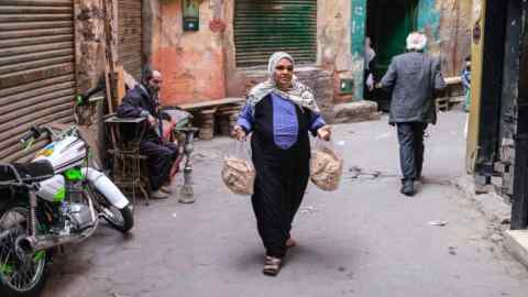 A woman carries bread down a lane in Cairo. With an estimated 60mn people living below or just above the poverty line, the state is already failing its citizens