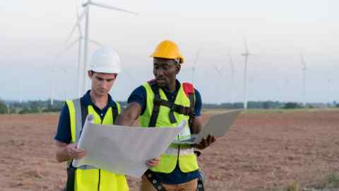 engineers in a wind farm consulting a blueprint