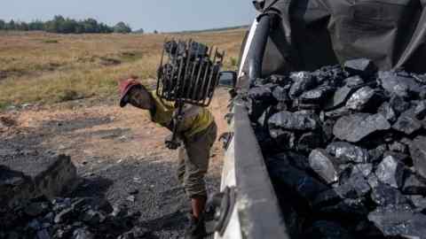 A man shovels coal into a truck with a pitchfork