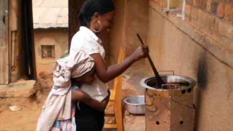 A woman and her child standing in front of an Atmosfair cookstove