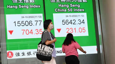 Pedestrians pass a sign showing figures for the Hong Kong Hang Seng index