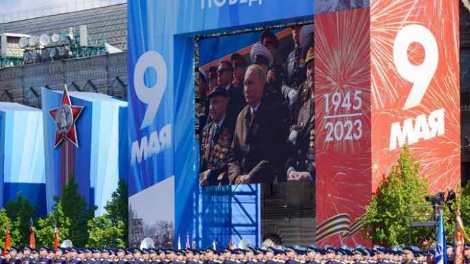 A giant screen shows Russian president Vladimir Putin looking on as soldiers line up in Red Square during the Victory Day military parade in Moscow on Tuesday