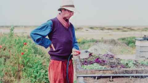 Derek Jarman waters his garden at Prospect Cottage, Dungeness