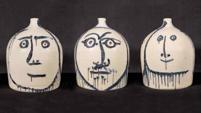 Three round cream-coloured vases roughly painted with faces in dark blue