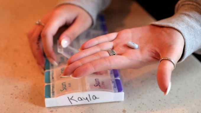 Kayla Krumrey, 21, of St. Charles, holds up a pill that she takes for her cystic fibrosis