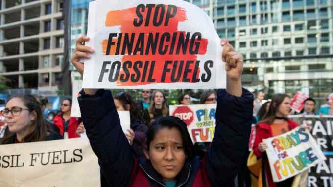 Demonstrator holding up a sign that says ‘Stop financing fossil fuels’
