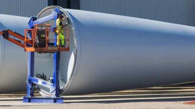 An employee checks the perimeter edging of a wind turbine blade manufactured by Danish company Vestas