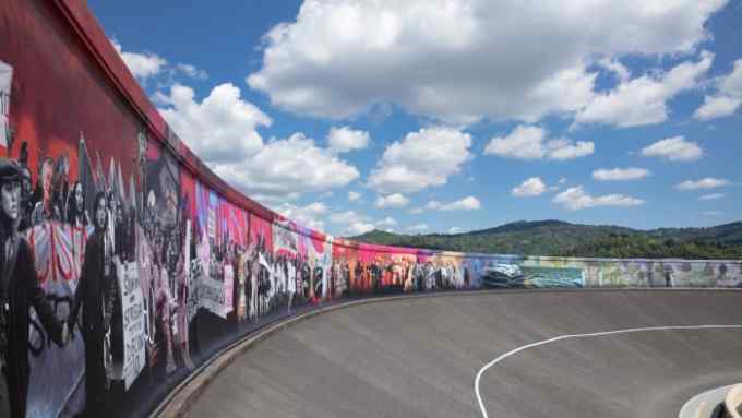 View along a busy mural curving a race track under a blue sky