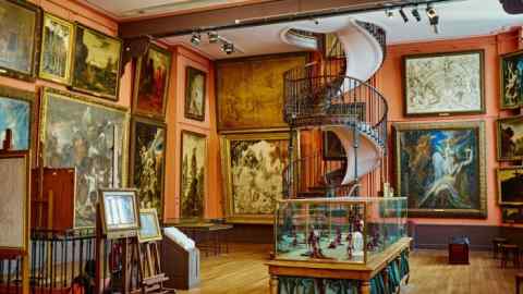 A room with paintings on the walls and a spiral staircase in the middle