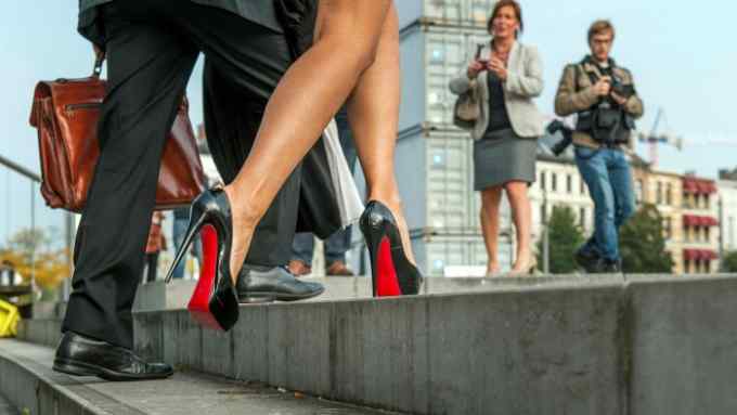 A woman stepping on to a step wearing high heels with red soles