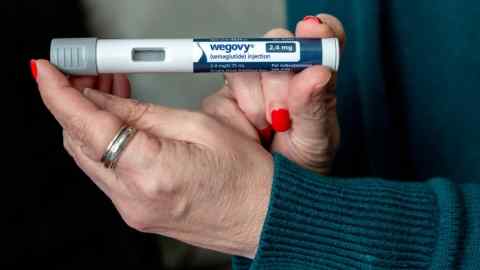 A person holding up a Wegovy injection
