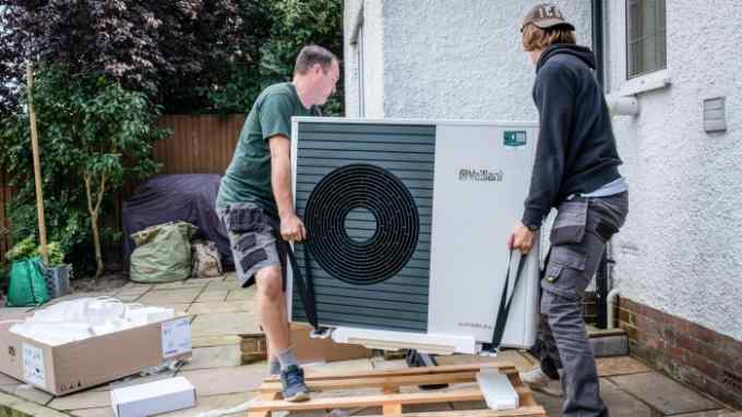 A photo of two men installing a heat pump