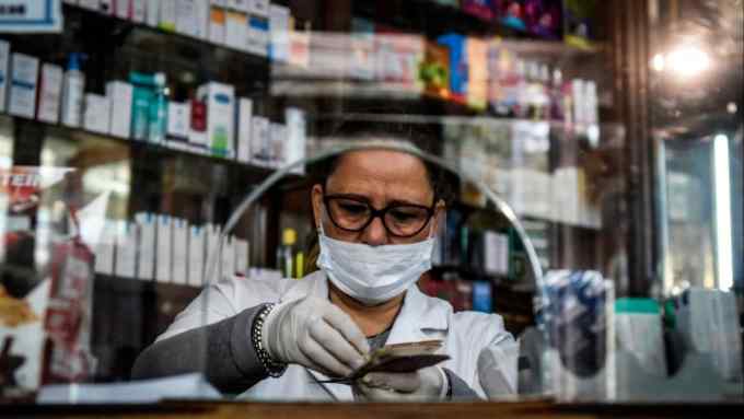 Pharmacy cashier Silvia Carballo wearing a face mask and gloves counts bills at ‘Farmacia de la Estrella’ on April 08, 2020 in Buenos Aires