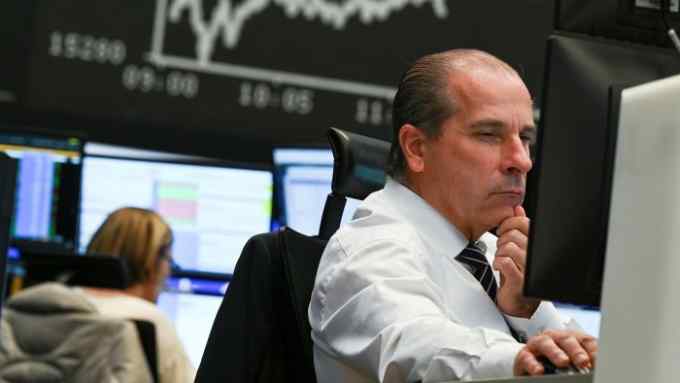 A stock trader looks at his monitors in the trading room of the Frankfurt Stock Exchange