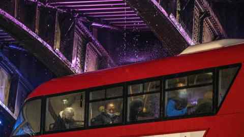 Passengers sit on a London bus under Waterloo Bridge
