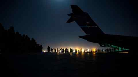 US air crew assist evacuees into a transport plane at Kabul airport, August 21