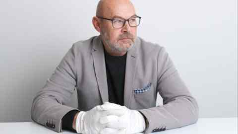 A man wearing white gloves with a watch in front of him