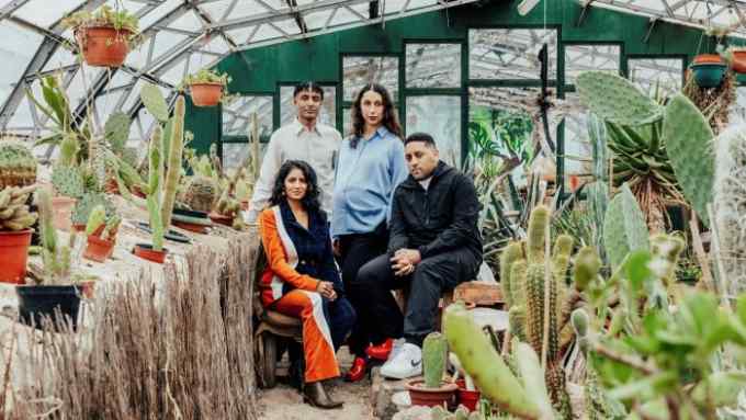 Four people pose in a greenhouse, surrounded by plants