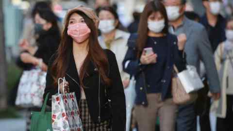 Shoppers wearing face masks to help curb the spread of the coronavirus at the Ginza shopping district in Tokyo