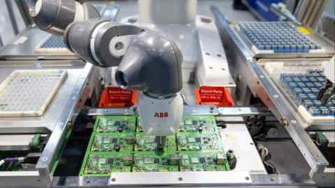 A robot arm places an item in the centre of a computer component board