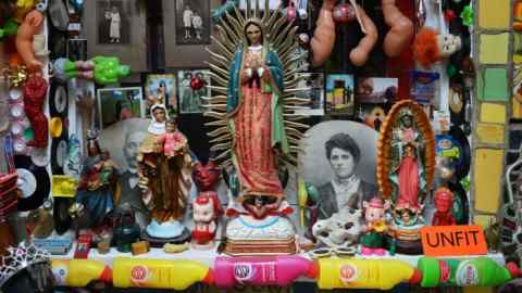 An altar filled with religious items, pictures and many other trinkets