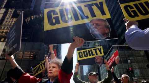 Anti-Trump protesters hold placards outside Trump Tower, the day after his guilty verdict