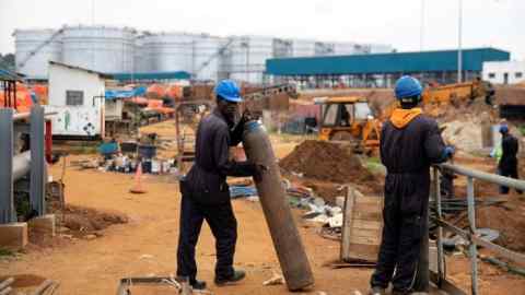 Workers prepare gas tanks for welding equipment at a new fuel storage complex in Entebbe, Uganda