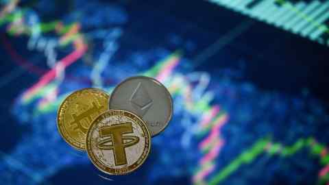 Tether, Bitcoin and Etherium coins arranged beside a screen displaying a trading chart