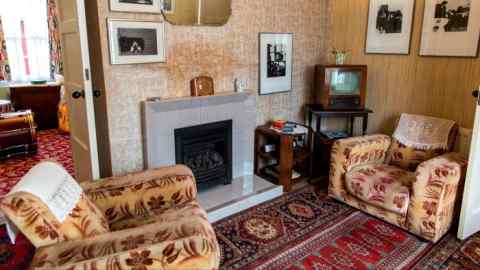 Two 1950s-style armchairs and a tiled fireplace with hanging mirror above