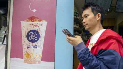 A man with a mobile phone walks past a Chabaidao bubble tea outlet in Shanghai, China